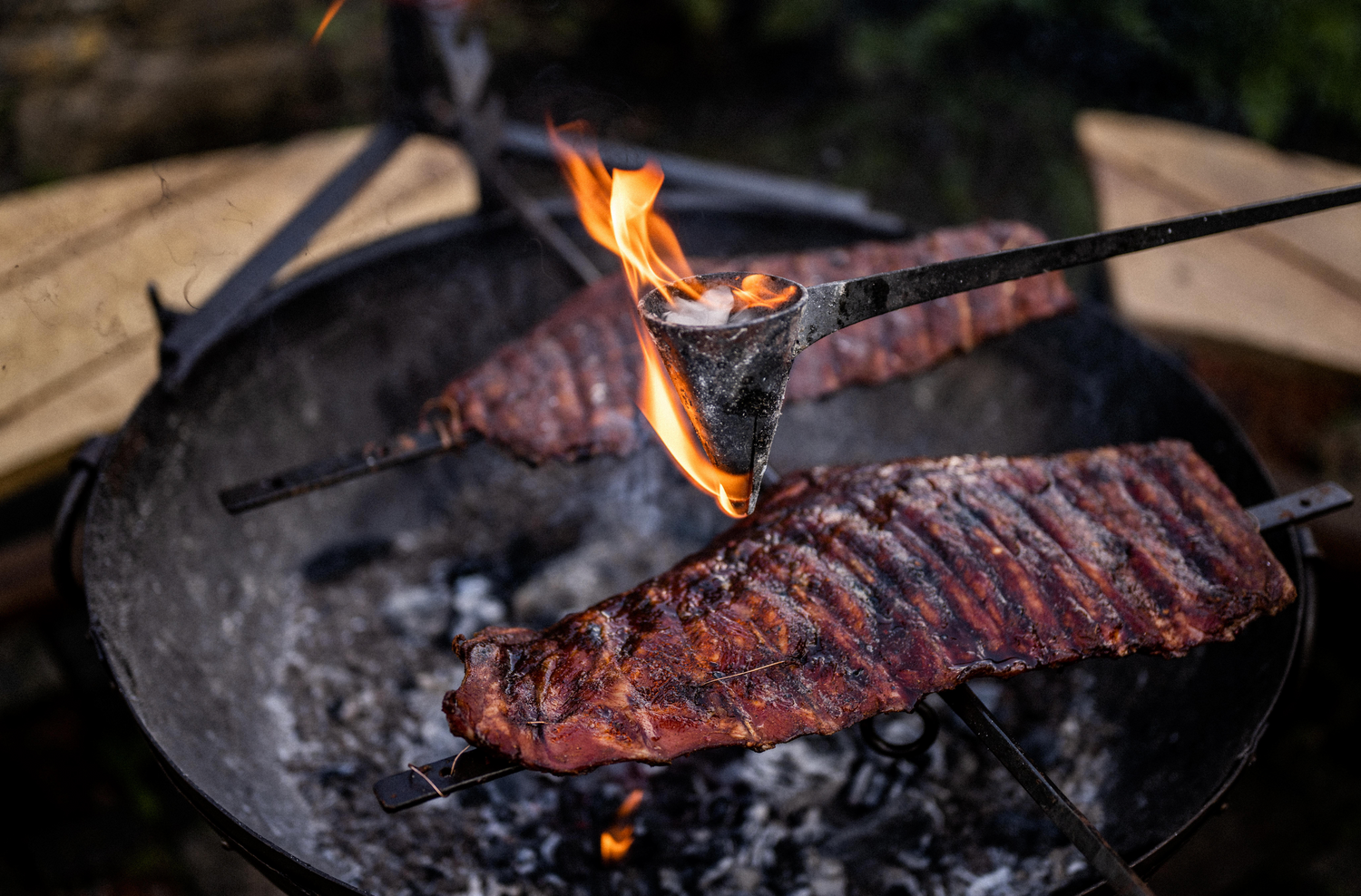 Beef ribs being cooked on a asado frame over a bbq