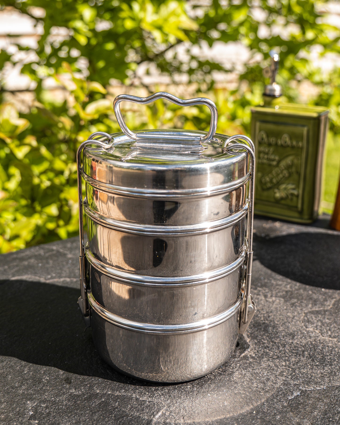 Metallic lunch box with a handle on a stone surface outdoors