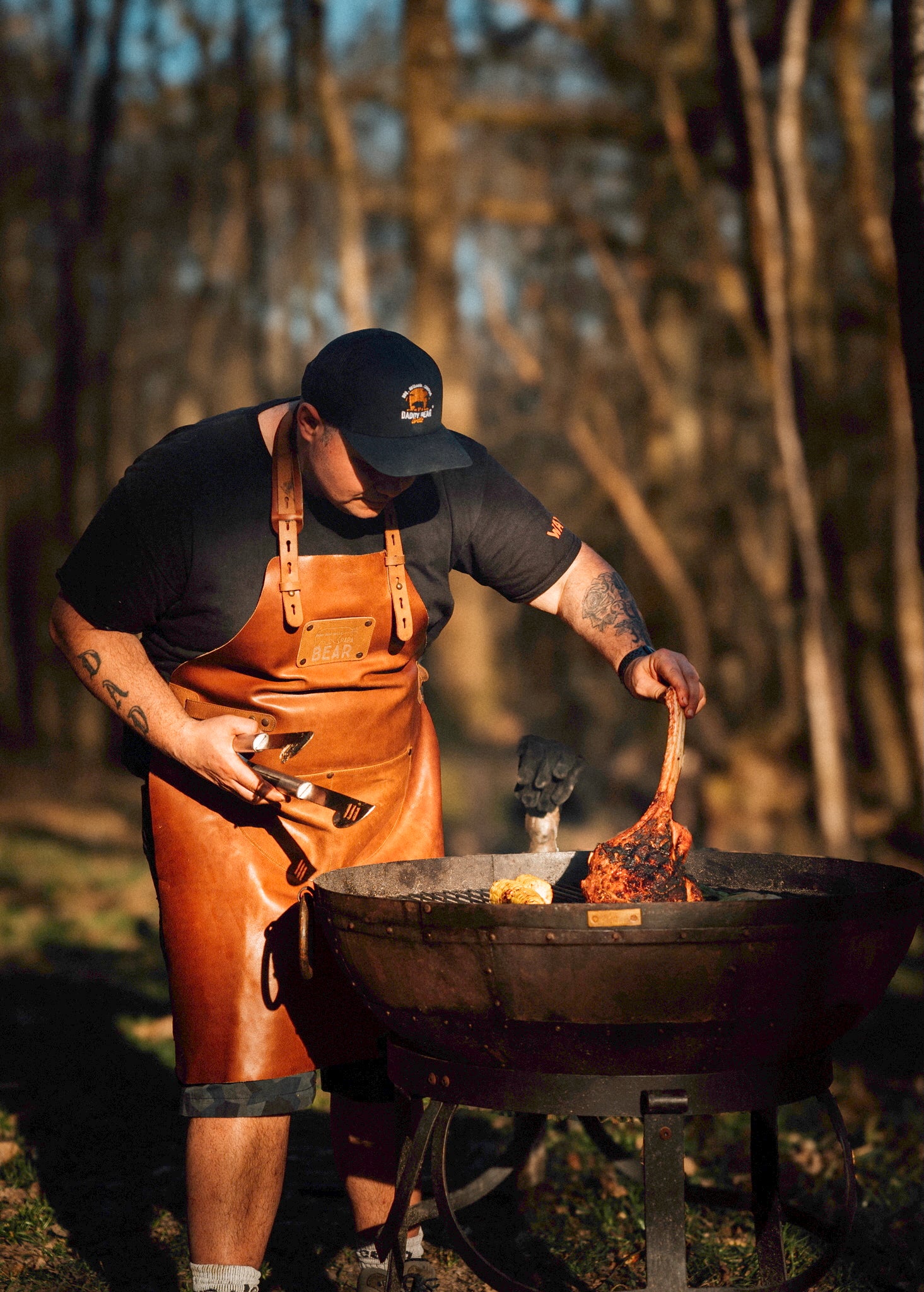 Person cooking over an open fire in a forest setting