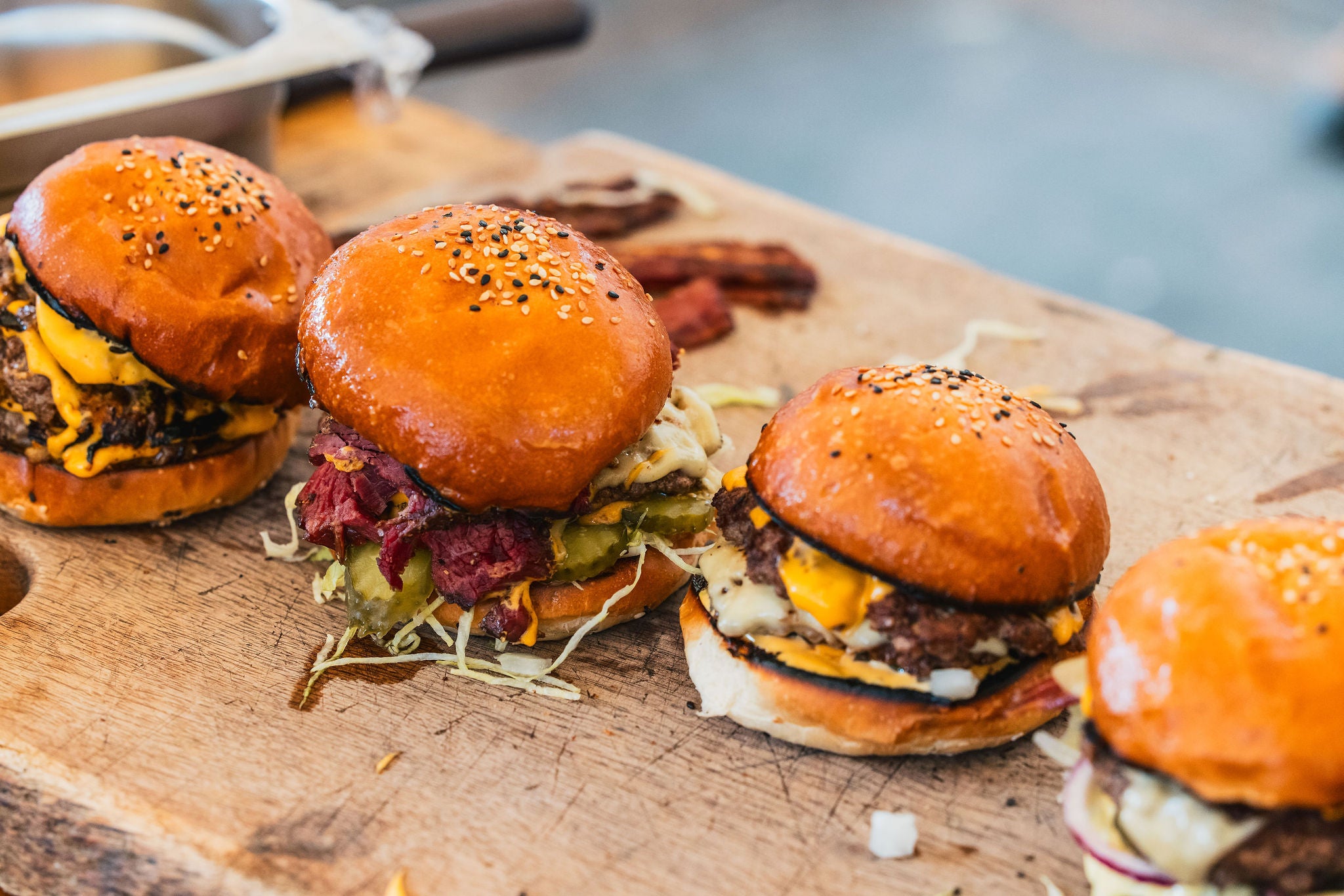 Four burgers on a kadai chopping board with a blurred background