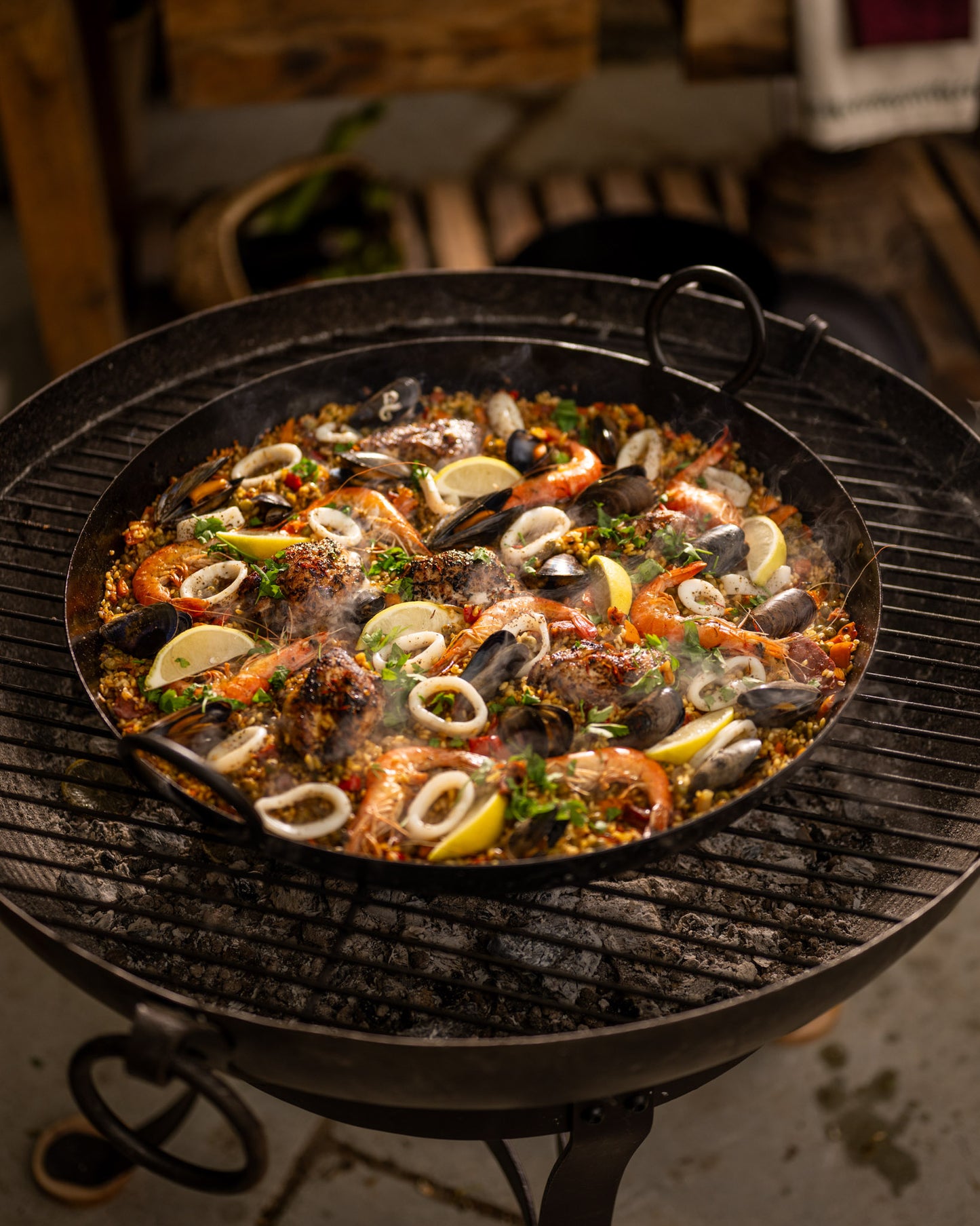 Seafood dish with shrimp, mussels, and lemon wedges on a BBQ in a Paella Pan.