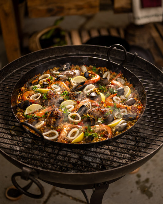 Seafood dish with shrimp, mussels, and lemon wedges on a BBQ in a Paella Pan.
