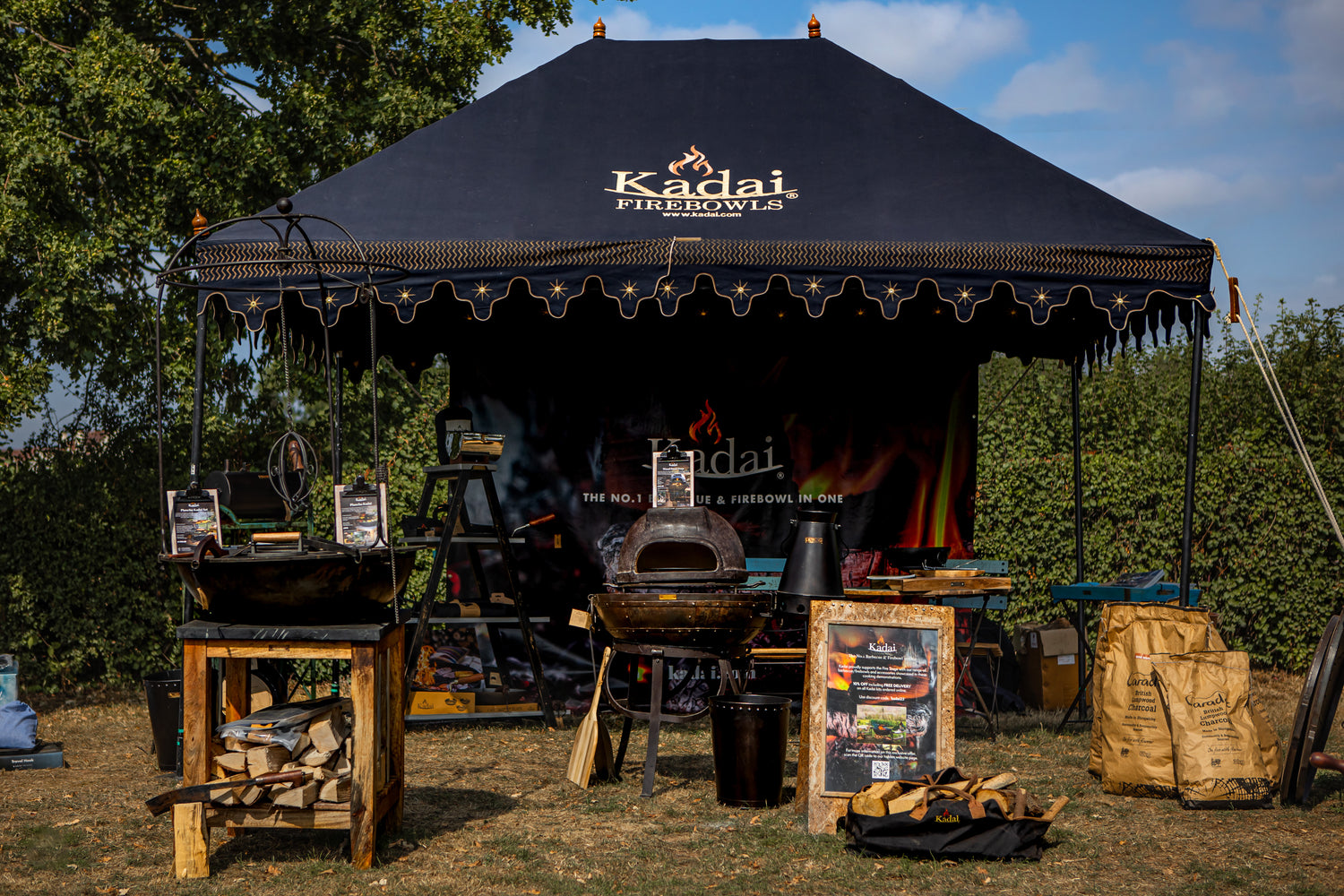 Kadai Firebowl stand with outdoor cooking equipment under a black canopy.