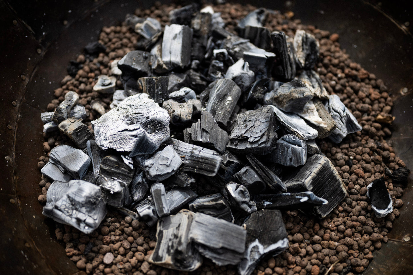 Close up of lit charcoal inside a metal fire pit.