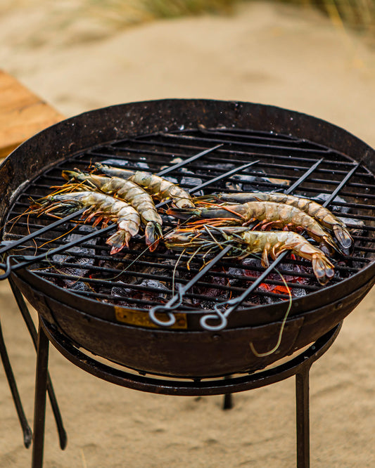 Shrimp being grilled on a black barbecue grill outdoors.