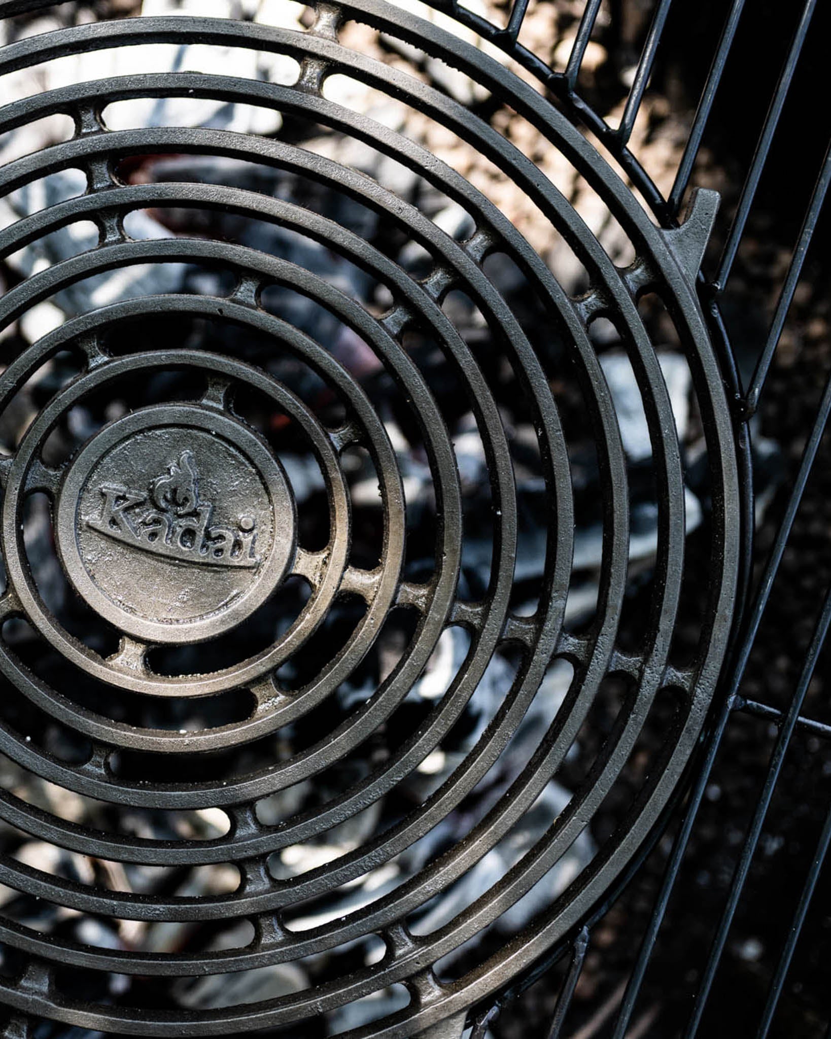 Close-up of a circular stone griddle plate with concentric grill design over glowing coals