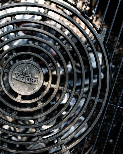 Close-up of a circular stone griddle plate with concentric grill design over glowing coals