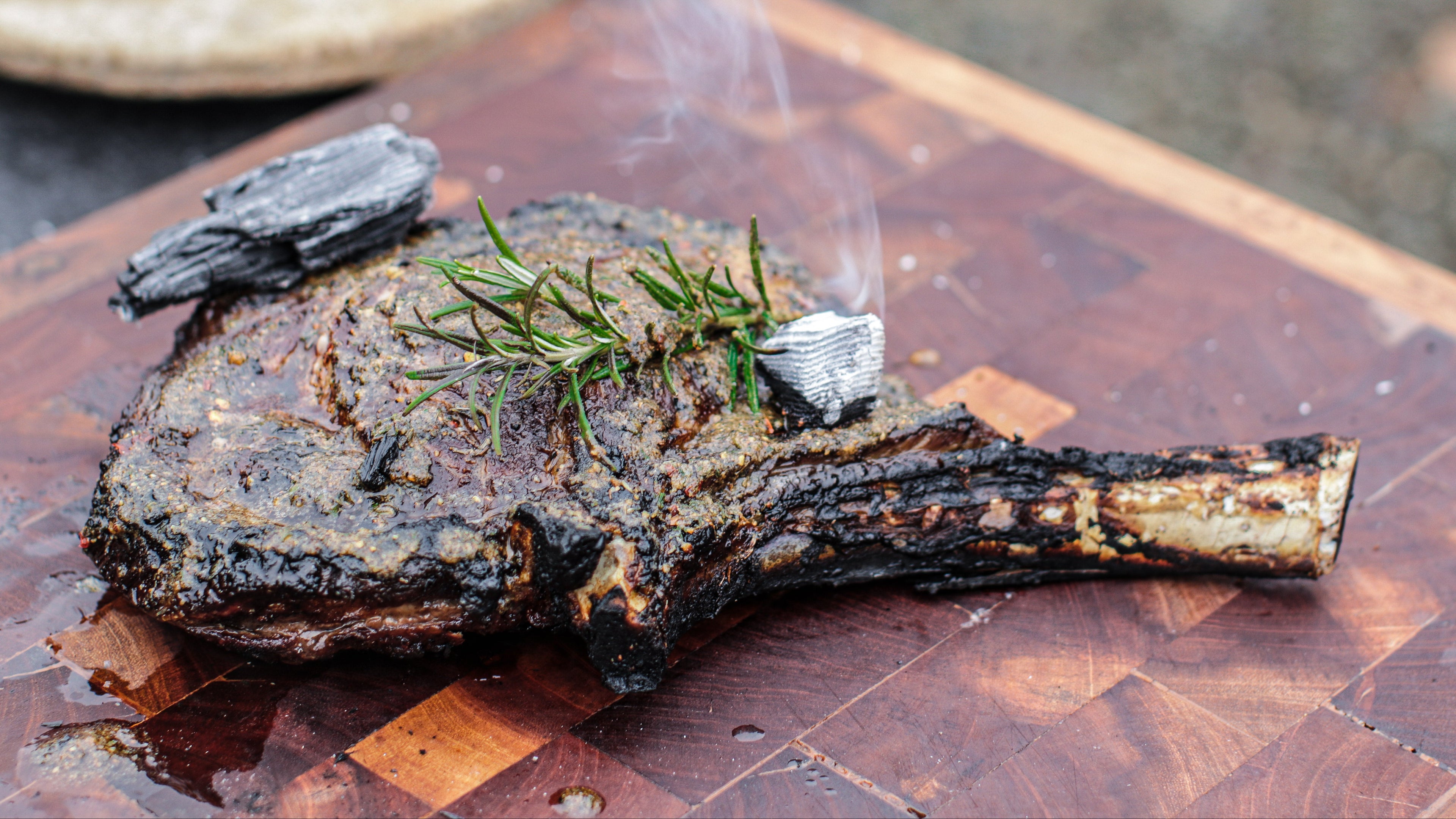 Grilled ribeye steak on a wooden cutting board with a blurred background