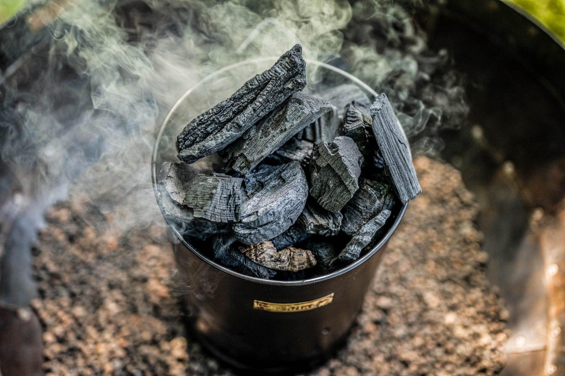Close-up of a charcoal starter chimney packed with hot smoking charcoal ready for outdoor grilling and fire pit cooking