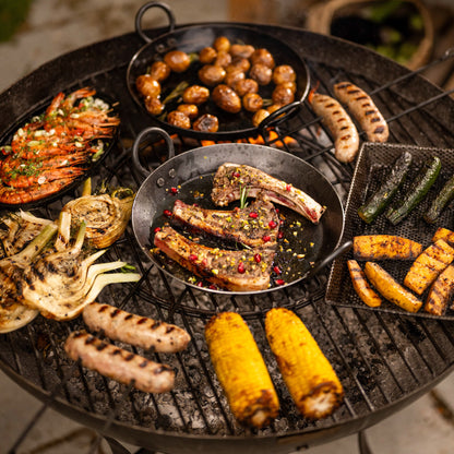 Assorted grilled meats, vegetables, and corn on a kadai barbecue grill.