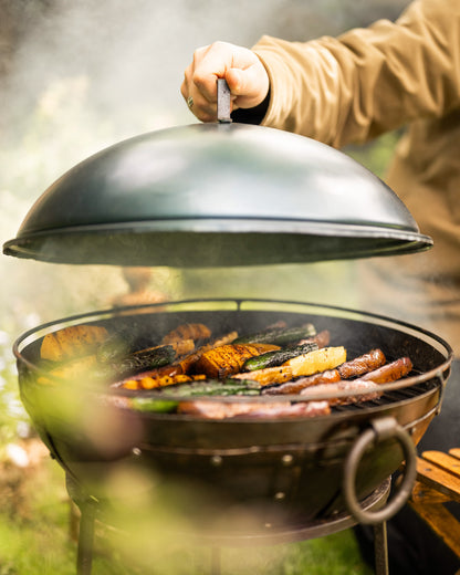 Detail of a portable BBQ lid showing adjustable airflow vent and handcrafted metal finish