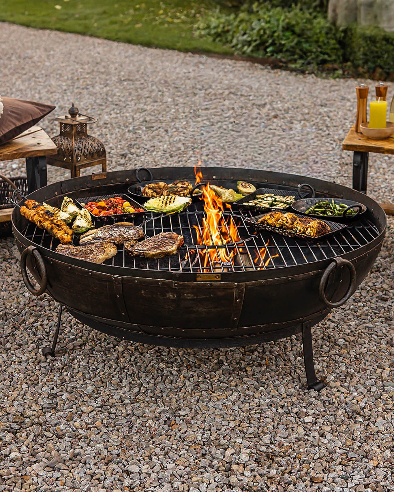 large recycled kadai with hot flames and array of vegetables and meats cooking