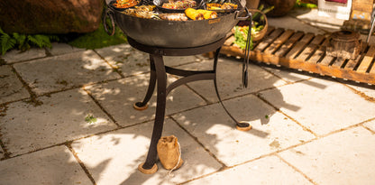 Kadai fire pit wooden feet protecting stone patio surfaces, designed to reduce heat transfer and provide stable support for outdoor fire bowl cooking and entertaining