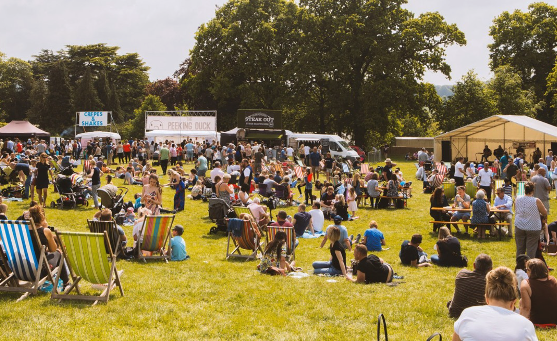 People enjoying a sunny day outdoors in a park with tents and chairs.