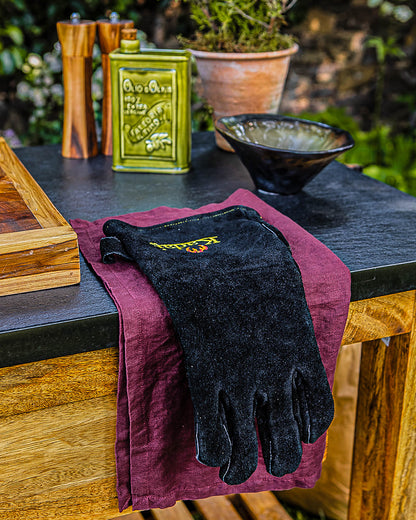 Protective BBQ glove displayed on a kitchen counter with oil bottle and utensils in the background