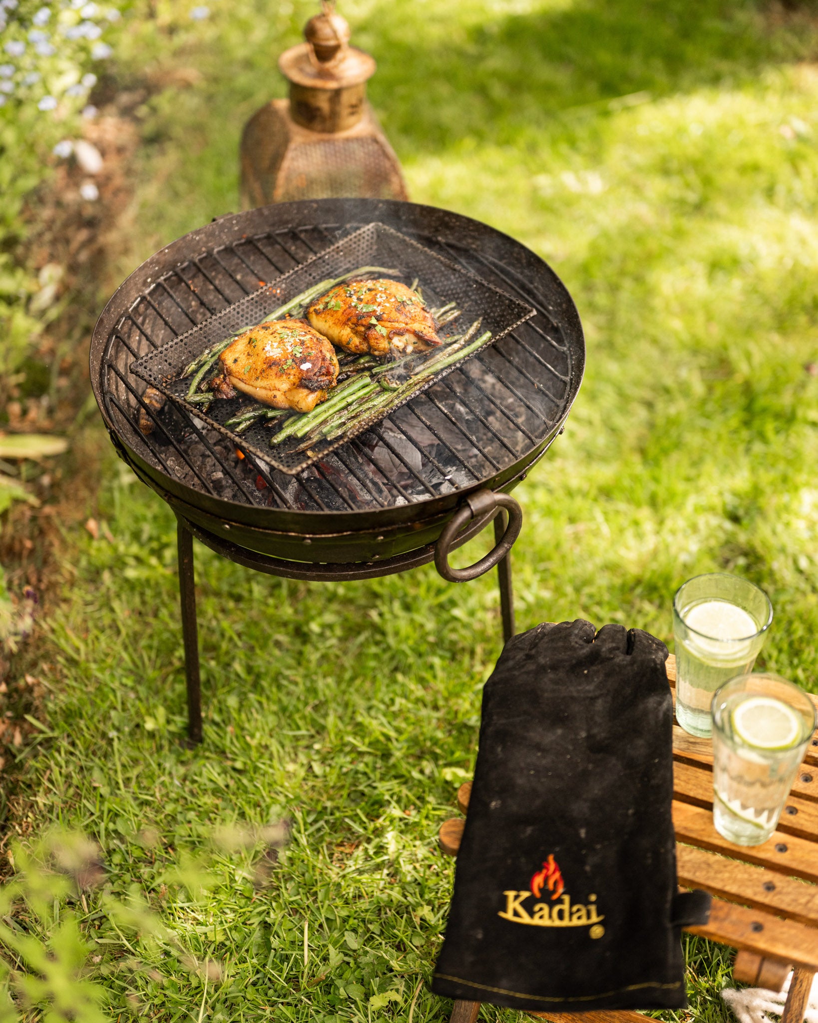 Outdoor grill with food on a grassy area, with a Grill Tray and cooked Chicken