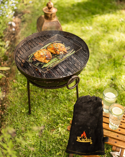 Outdoor grill with food on a grassy area, with a Grill Tray and cooked Chicken