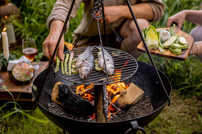 BBQ swing grill with whole fish and asparagus cooking over an open fire