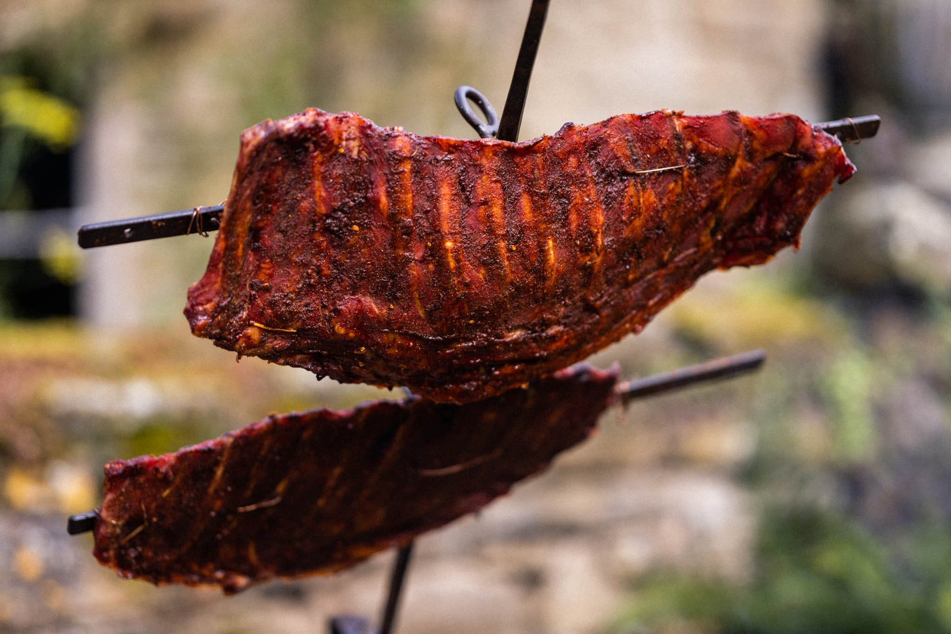 Marinated ribs slow-cooking on a traditional asado cross over an open fire