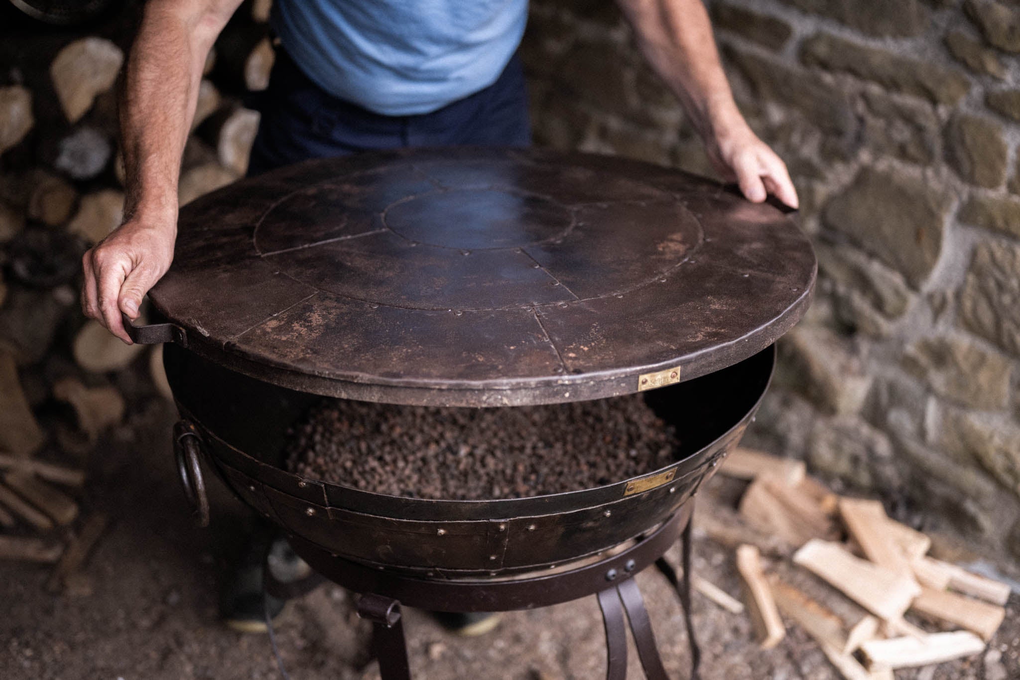 Person placing kadai lid on recycled firebowl