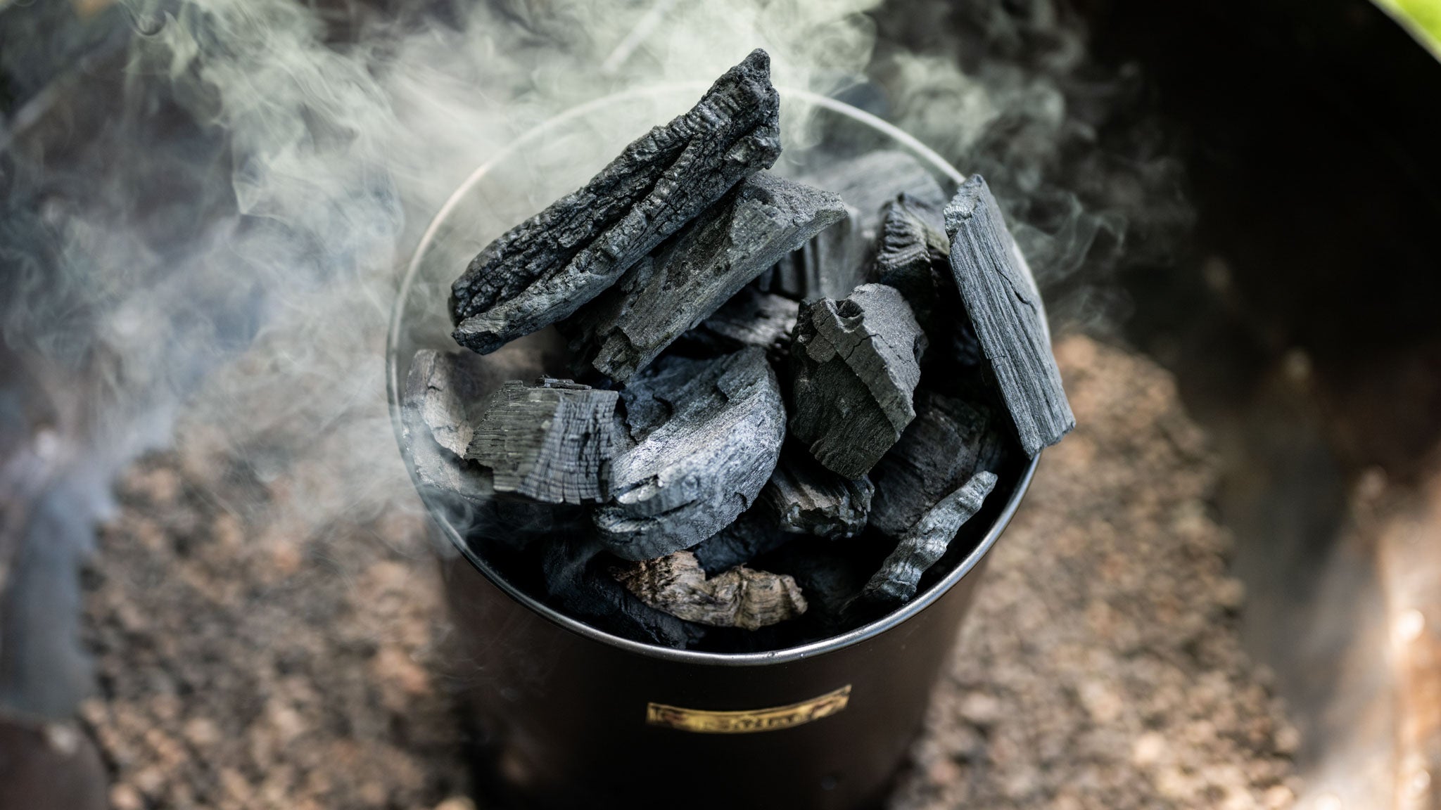Charcoal briquettes in a kadai charcoal maker with smoke rising