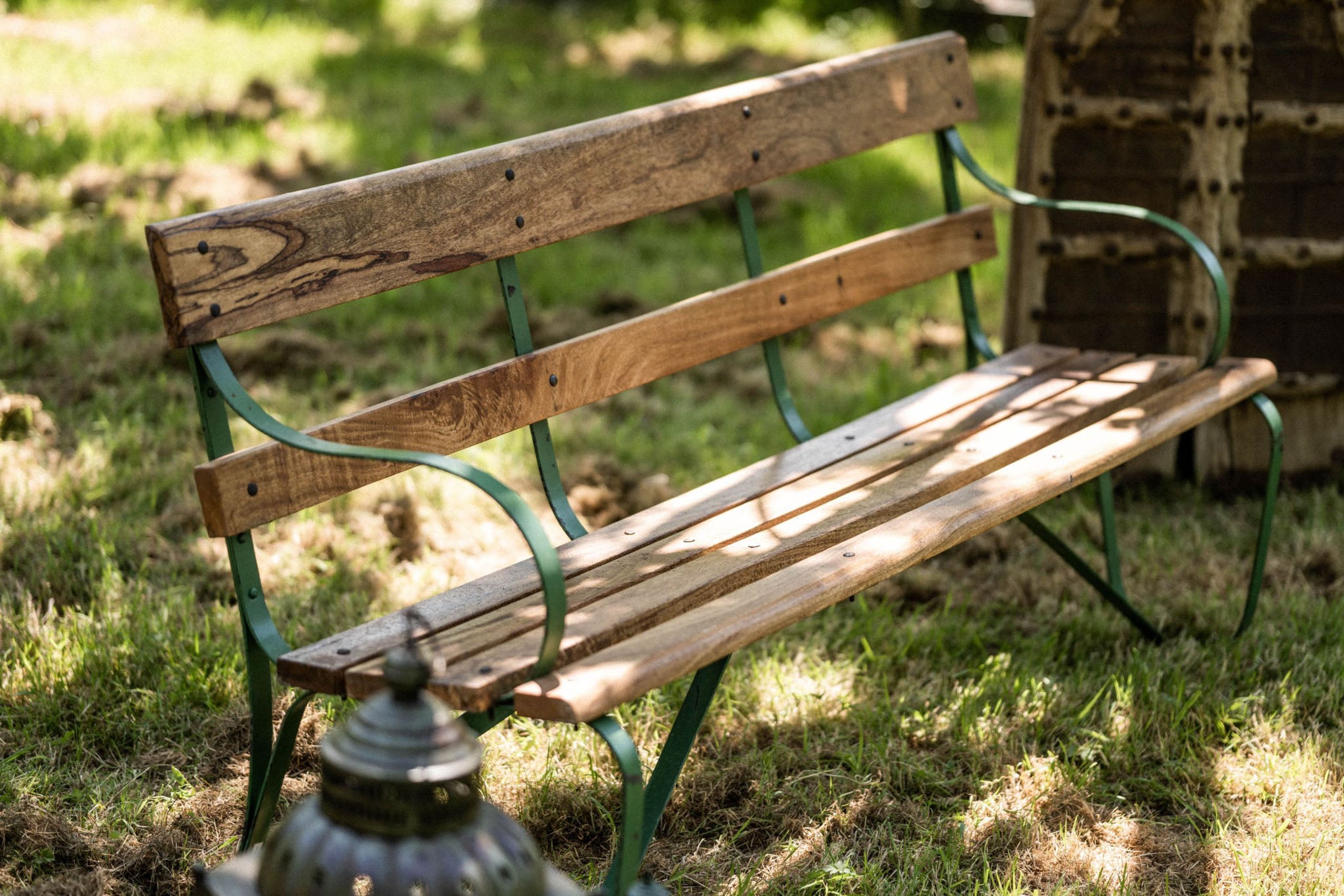 Wooden bench with green metal frame on grass