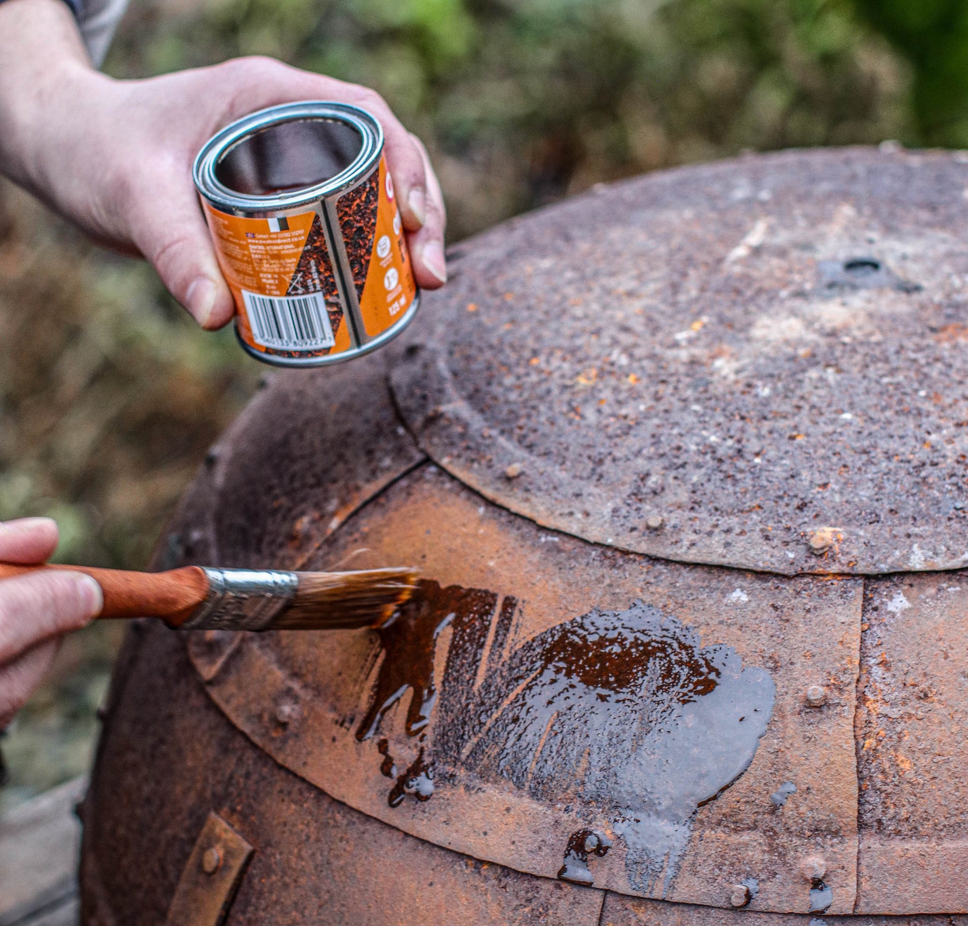 Applying protective oil to a rusted Kadai fire bowl using a brush from a Kadai Care Kit