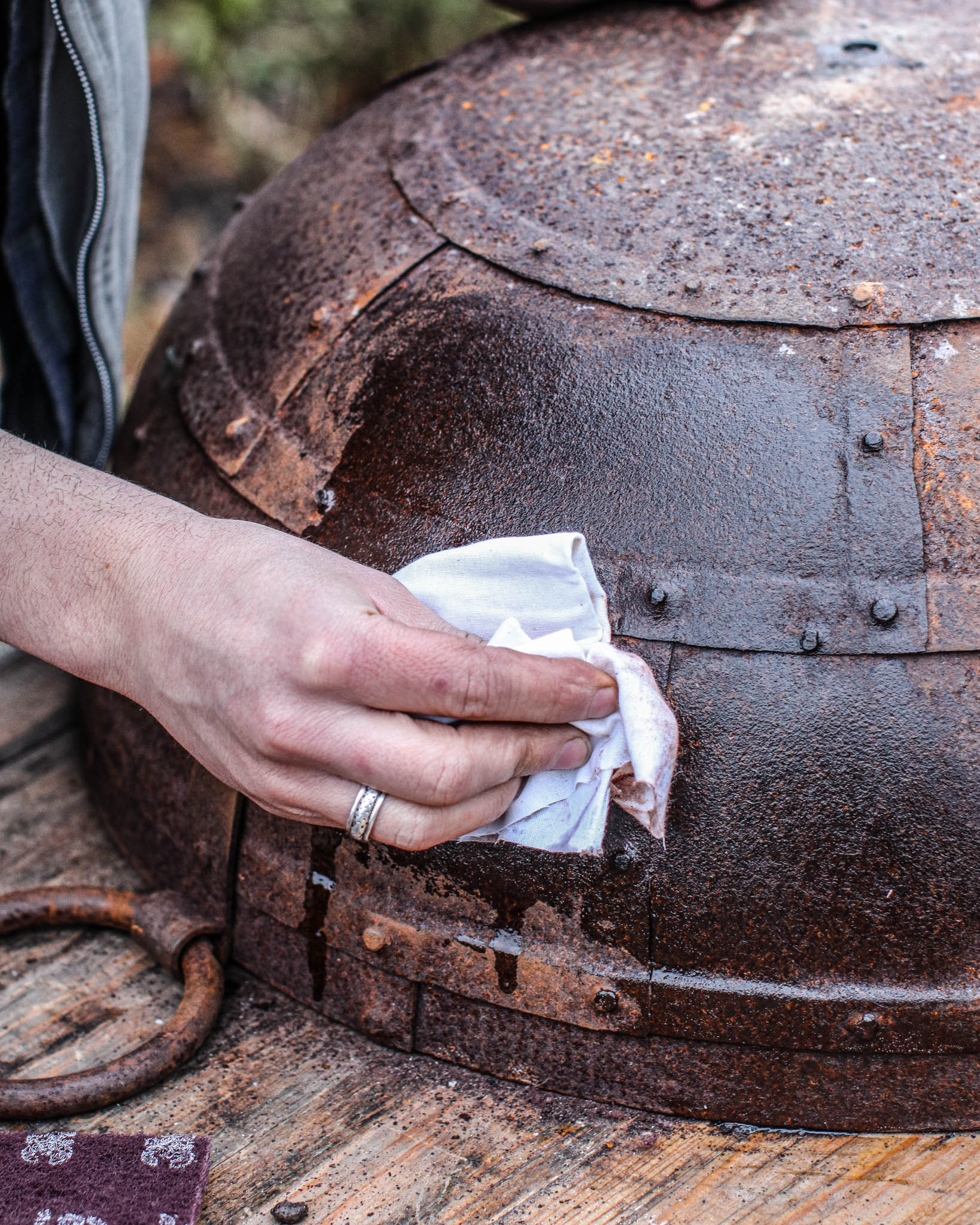 Person wiping and polishing a restored Kadai fire bowl with a cloth as part of routine maintenance