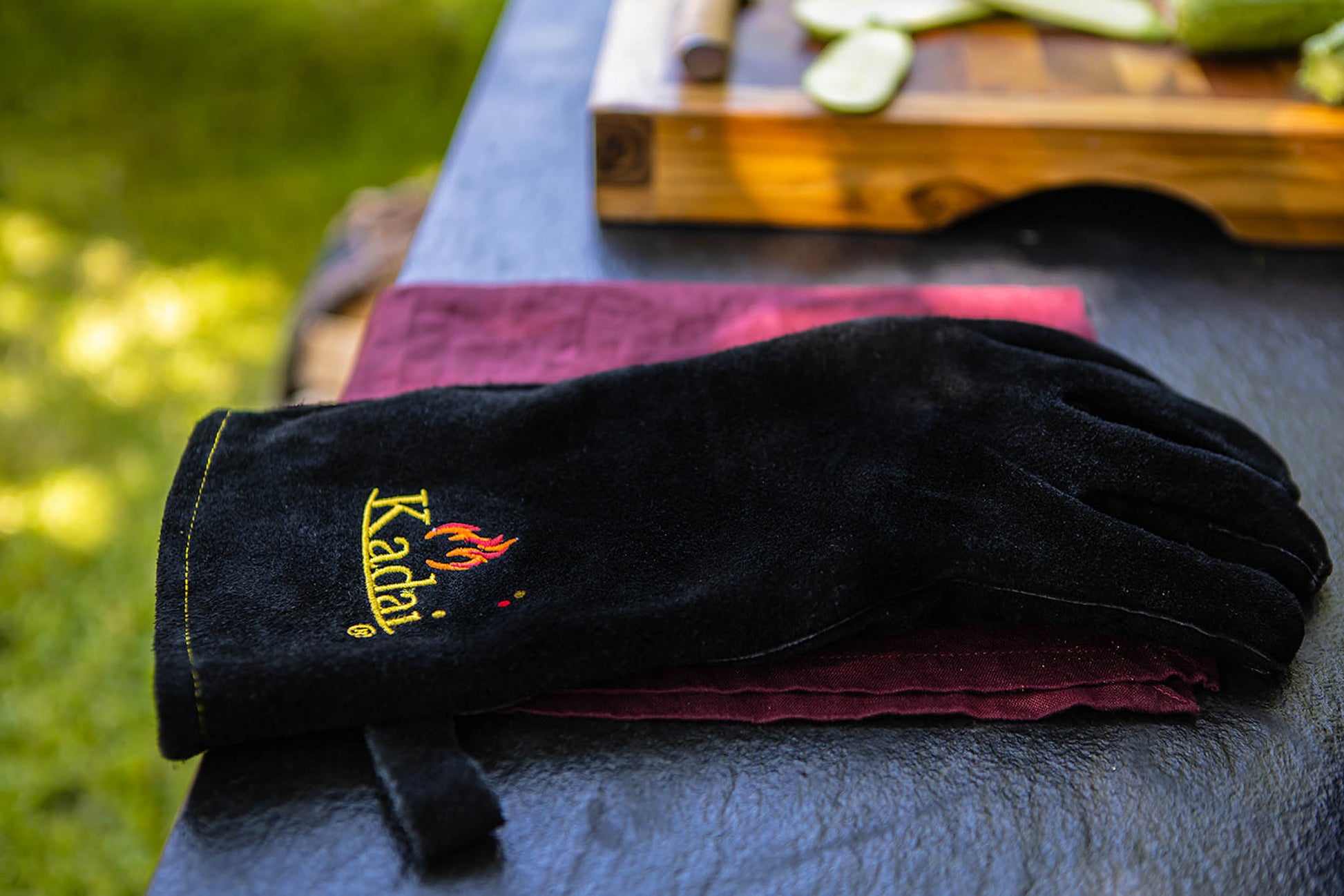 Black kadai heat-resistant glove resting on a folded cloth on an outdoor table