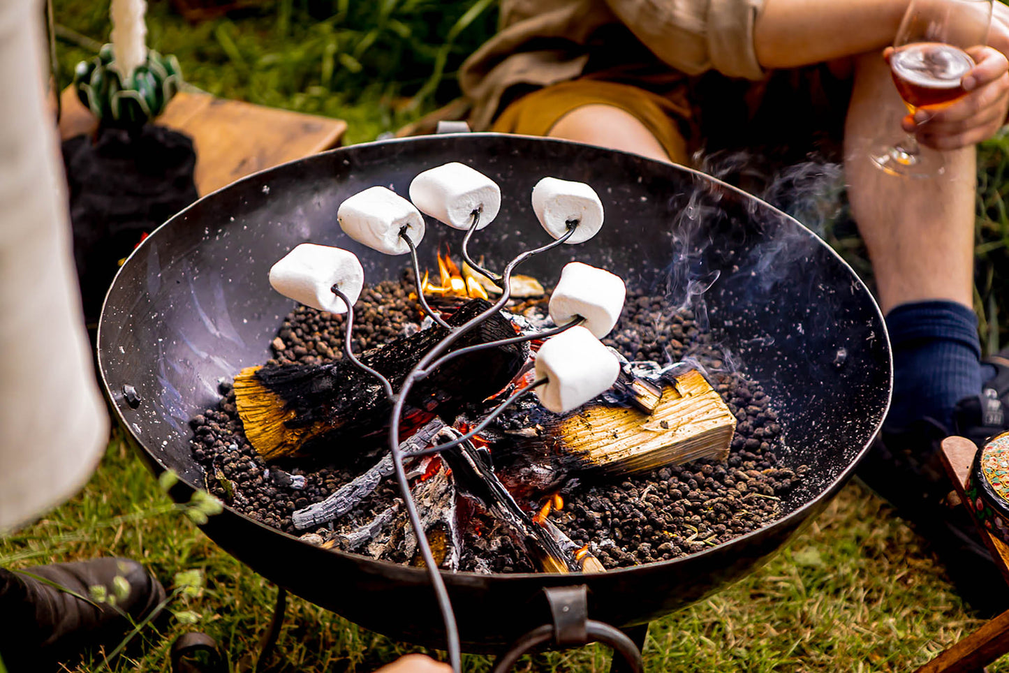 Close-up of marshmallow roasting forks warming treats above glowing embers during an outdoor fire pit gathering