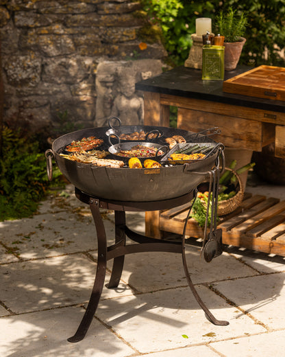 Modern BBQ fire pit on a patio with a grill full of food
