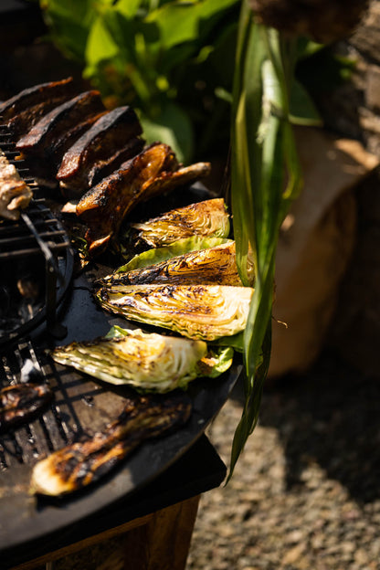 Grilled cabbage wedges and vegetables cooking on a plancha kadai grill