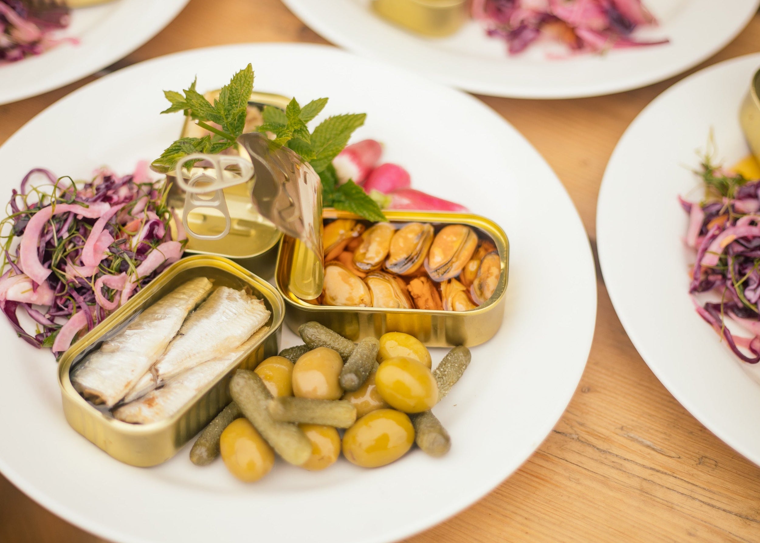 Plated dish with pickled vegetables and small containers on a wooden table