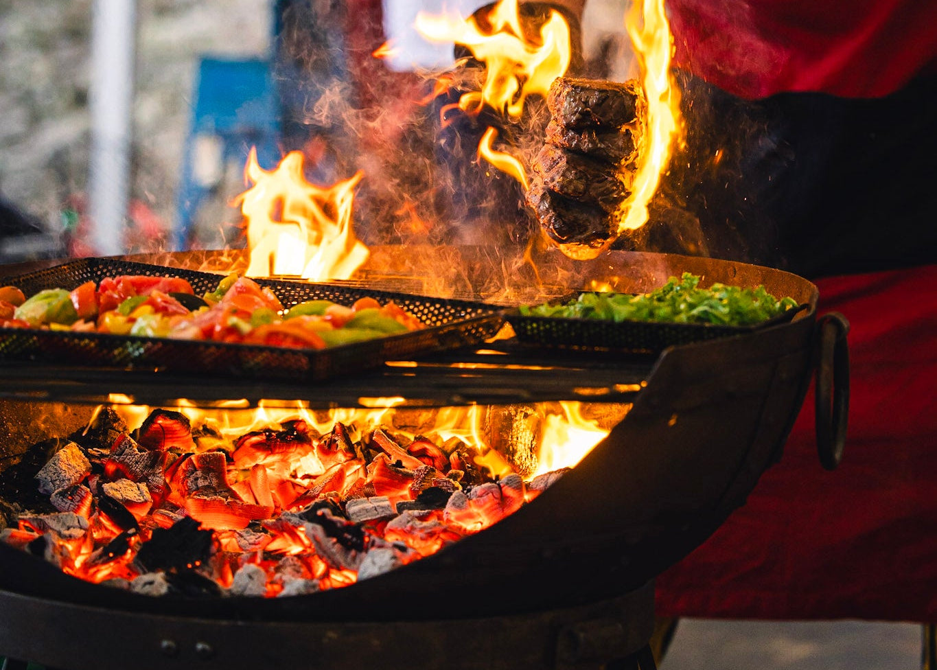 Person grilling food over an open flame Kadai with a blurred background