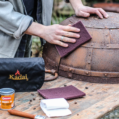 Using a Kadai Care Kit to restore and protect a metal fire pit with cleaning pads, oil treatment, and cloths