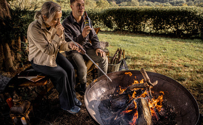 Two people cooking over an open fire in a natural setting