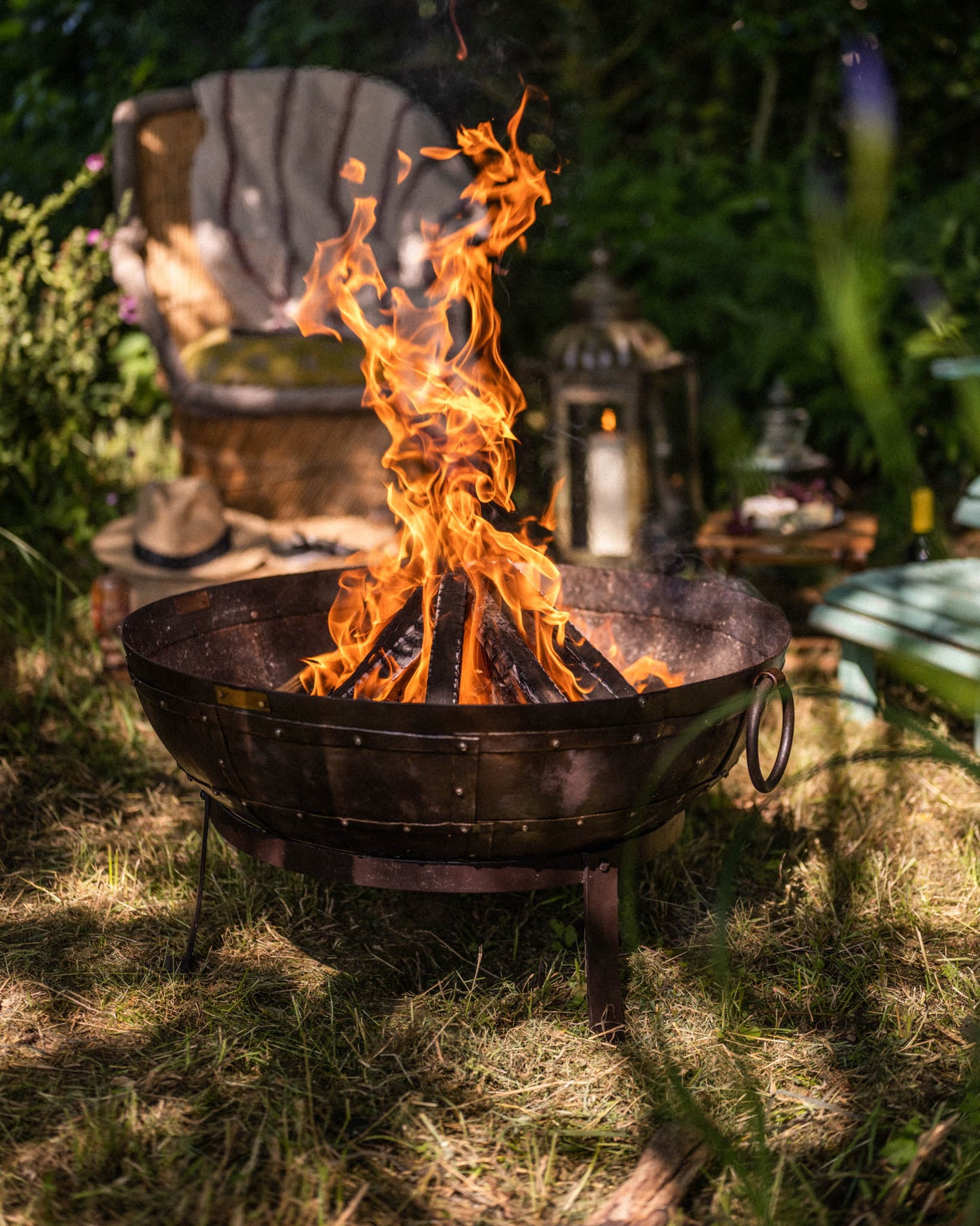 Medium sized charcoal BBQ fire bowl with tall flames burning in garden setting