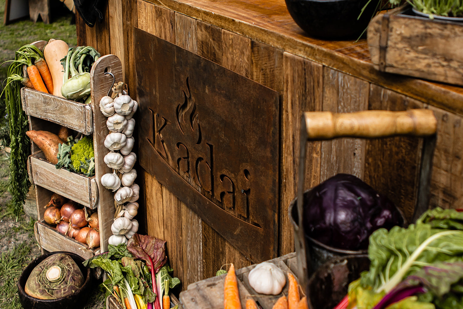 Wooden counter with vegetables and a decorative sign reading 'kadai'.