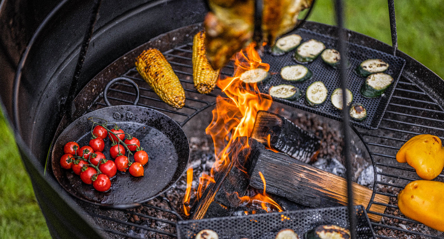 Close-up of Kadai BBQ with wind guard panels, flames in the center and vegetables grilling around the edge