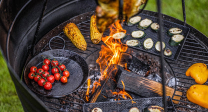 Close-up of Kadai BBQ with wind guard panels, flames in the center and vegetables grilling around the edge