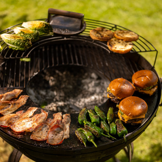 Barbecue grill with various foods including burgers, vegetables, and meats on a hot plate