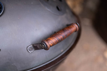 Close-up of wooden handle attached to a metal BBQ smoker lid