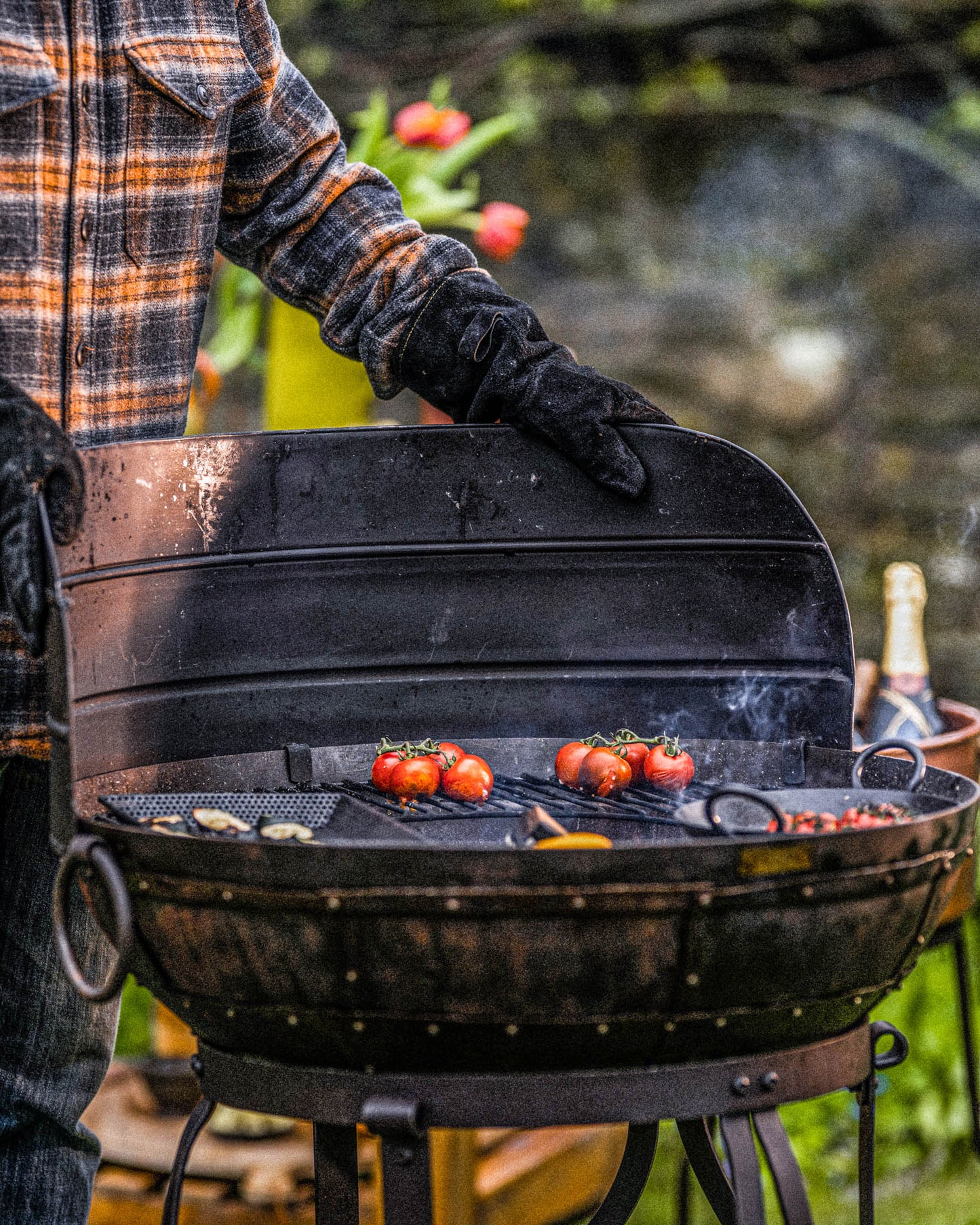Kadai fire pit barbecue with wind guard shield in place while grilling tomatoes and vegetables