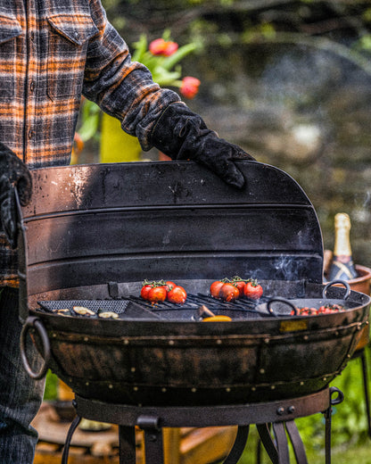Kadai fire pit barbecue with wind guard shield in place while grilling tomatoes and vegetables