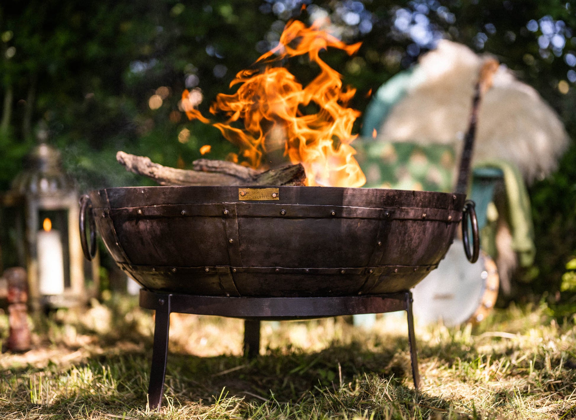 Medium sized charcoal BBQ fire pit with flames burning in Kadai fire bowl in garden setting