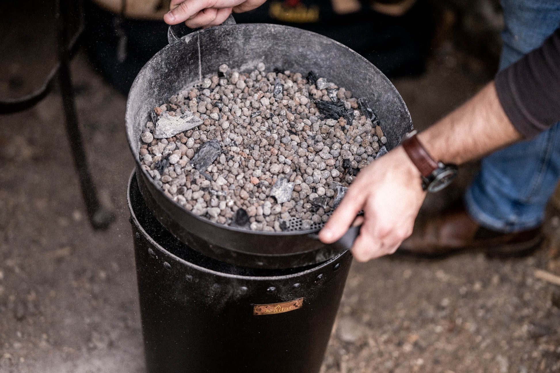 BBQ bin with charcoal sifter separating reusable charcoal from ash and dust after outdoor cooking on a Kadai barbecue
