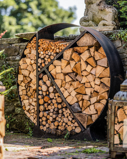 Modern round firewood rack organizing split logs beside a stone wall patio