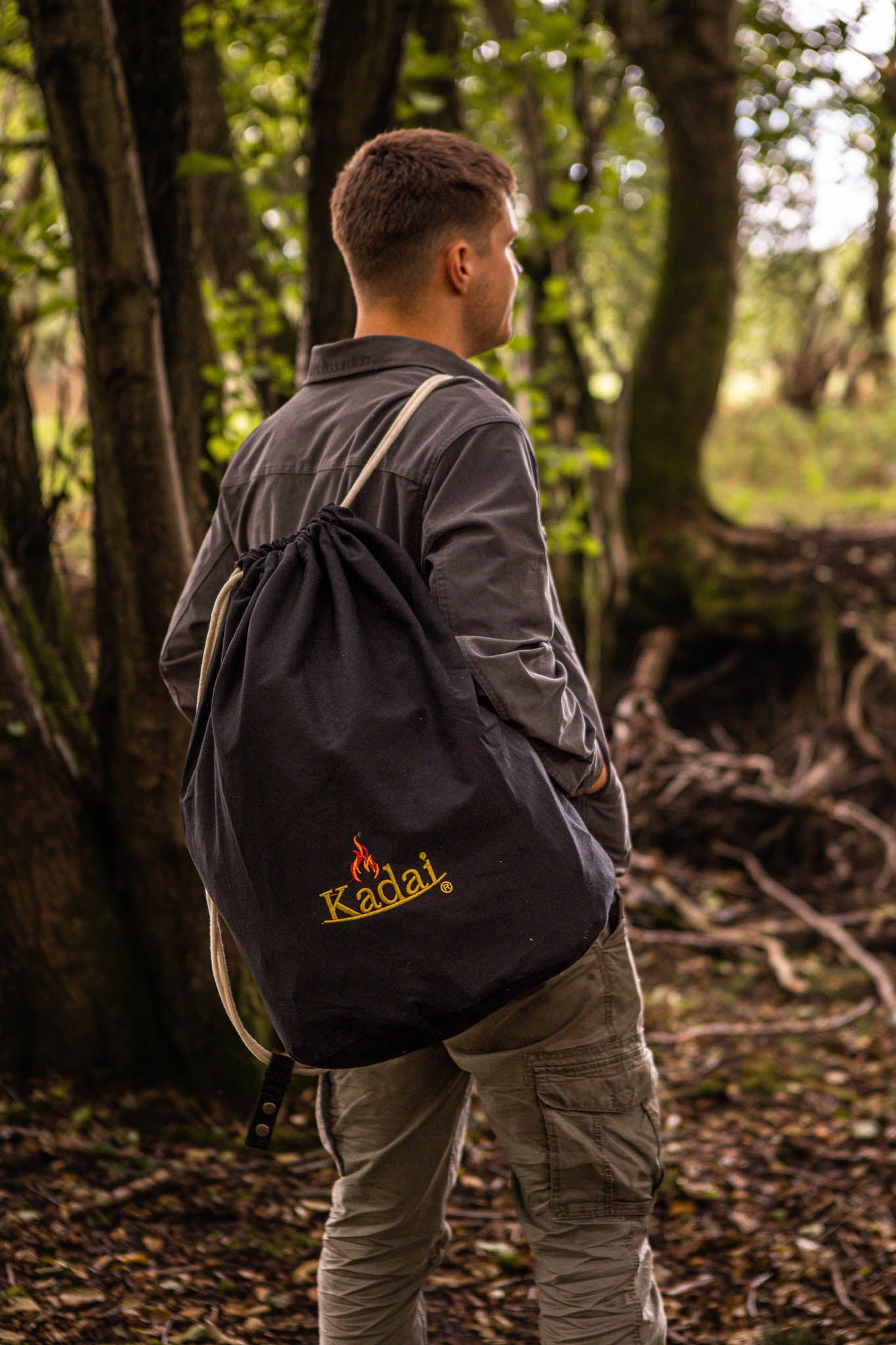 Kadai portable BBQ packed in a carry bag over the shoulder, person walking outdoors in a forest setting