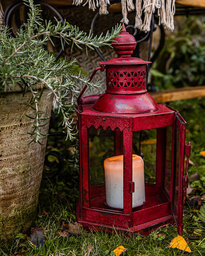 Red lantern with a candle inside on a table outdoors