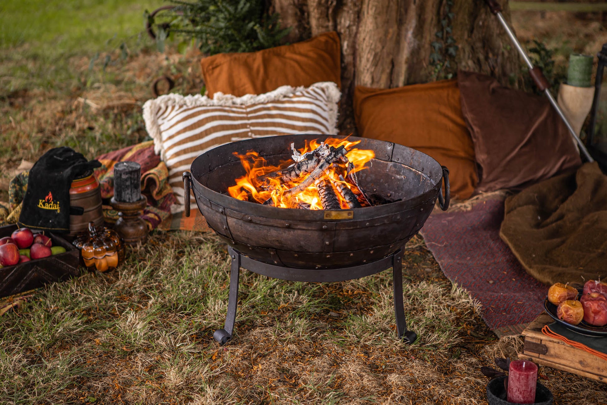 Recycled Kadai firebowl creating a warm outdoor setting beneath a tree, styled with blankets and cushions for relaxed evenings around the fire outdoors